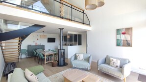 Un vaste espace de vie comprenant un escalier, une cheminée et un coin repas.