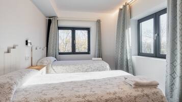 Een slaapkamer met twee bedden, een raam met gordijnen en een nachtkastje.