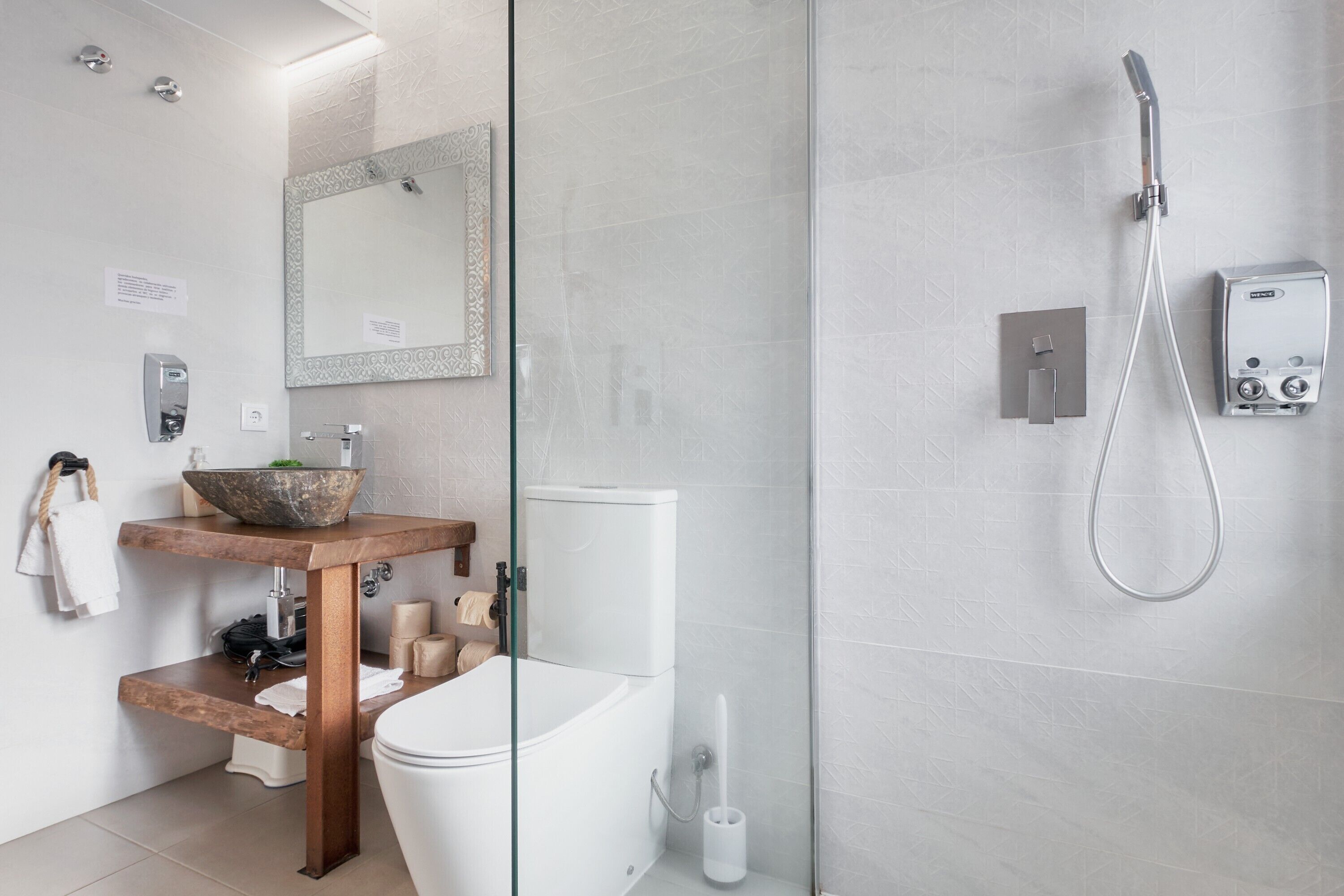 Ein modernes Badezimmer mit Duschkabine aus Glas, einem Holzwaschtisch, einer weißen Toilette und einem großen Spiegel.
