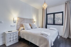 A neatly arranged bedroom with a bed, bedside lamps, a nightstand, and a window with curtains. - Apartment 'Marel' with Mountain View, Wi-Fi and Air Conditioning (Cerdillo de Sanabria)