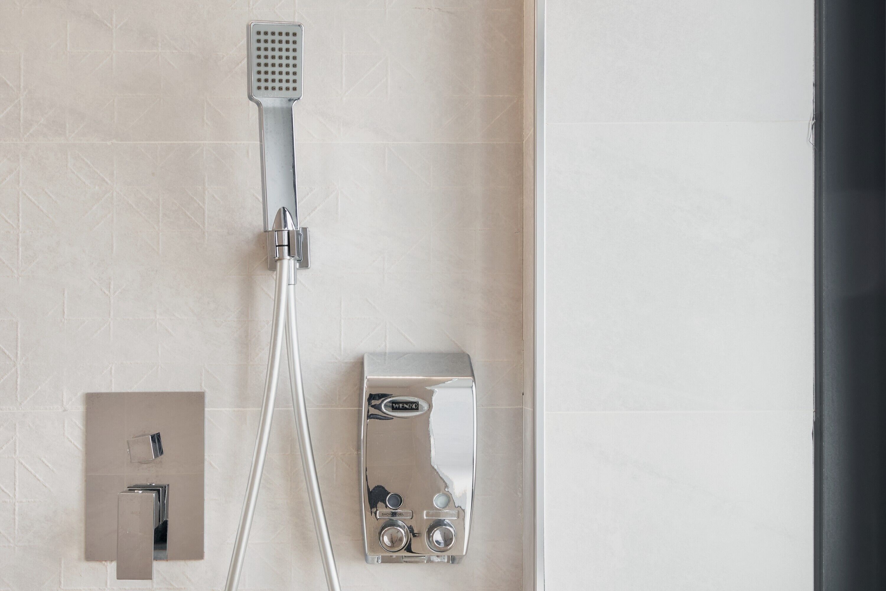 Un baño moderno con ducha, panel de control y llave de pared.