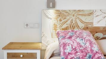 Ein Schlafzimmer mit einem hölzernen Nachttisch, einem Bett mit Blumenbord und einer Steckdose.