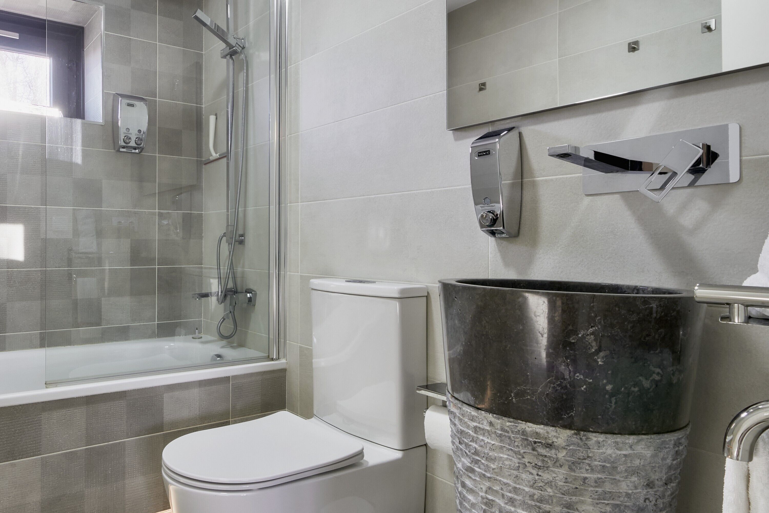 A modern bathroom with a glass-enclosed shower, a toilet, and a marble sink.