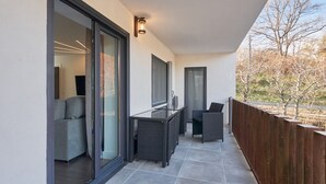 A balcony with a glass door, a table, chairs, and a wooden fence. - Apartment 'Marel' with Mountain View, Wi-Fi and Air Conditioning (Cerdillo de Sanabria)