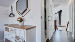 A hallway with a wooden dresser, a mirror, and a potted plant. - Apartment 'Marel' with Mountain View, Wi-Fi and Air Conditioning (Cerdillo de Sanabria)