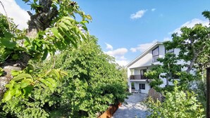 A modern two-story house with a balcony, surrounded by lush greenery and a stone wall. - Apartment 'Marel' with Mountain View, Wi-Fi and Air Conditioning (Cerdillo de Sanabria)