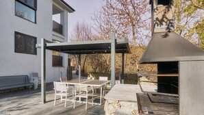 A patio with a grill, outdoor seating, and a building in the background. - Apartment 'Marel' with Mountain View, Wi-Fi and Air Conditioning (Cerdillo de Sanabria)