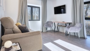 A modern living room with a sofa, a table, and two chairs. There is a flat-screen TV mounted on the wall. - Apartment 'Marel' with Mountain View, Wi-Fi and Air Conditioning (Cerdillo de Sanabria)