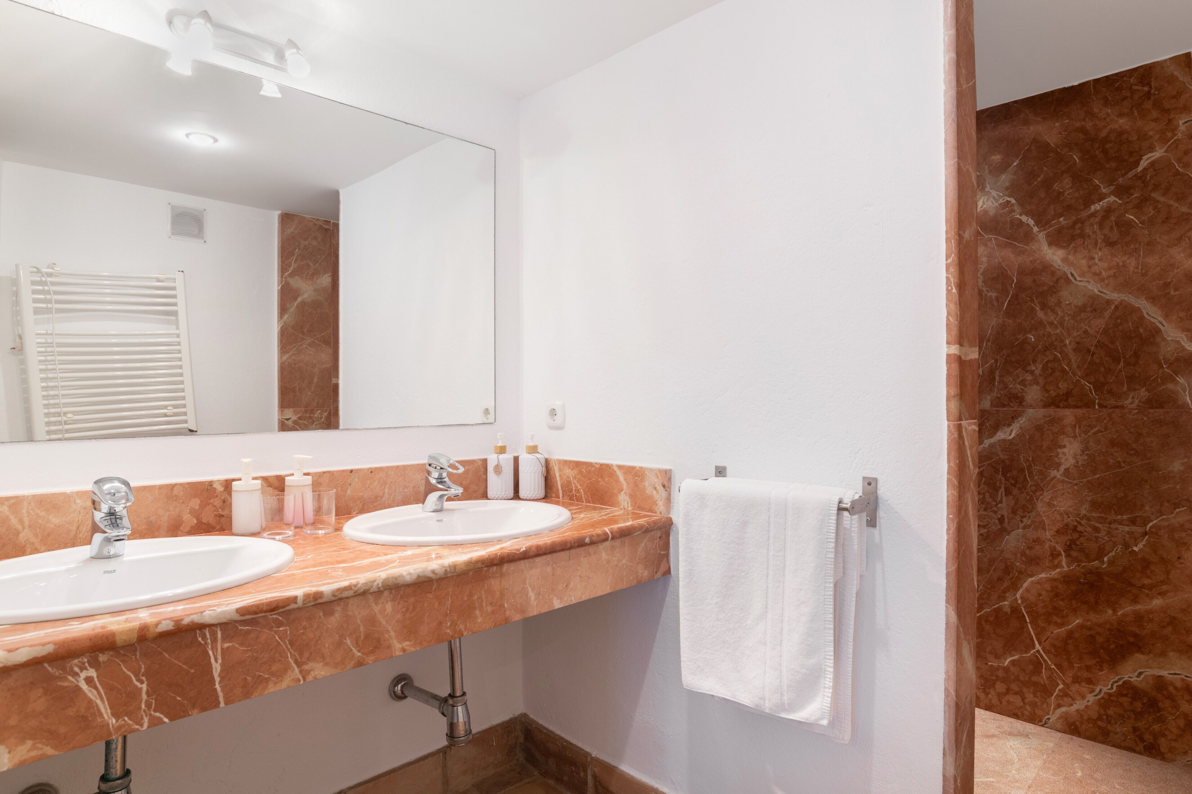 Ein Badezimmer mit zwei Waschbecken, einem großen Spiegel und einem Handtuchhalter.