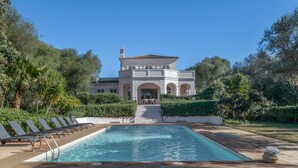 A pool with lounge chairs, a building with arches, and a clear blue sky. - Villa 'Eagle' with Private Pool, Wi-Fi, and Air Conditioning (Benalup-Casas Viejas)