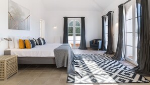 A bedroom with a bed, a rug, a side table, and a view of the outdoors through a window. - Villa 'Eagle' with Private Pool, Wi-Fi, and Air Conditioning (Benalup-Casas Viejas)
