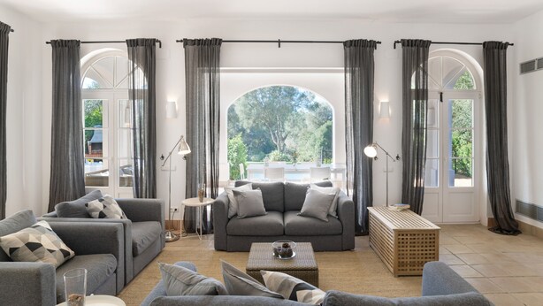 A living room with a grey sofa set, a coffee table, and a view through a large arched window. - Villa 'Eagle' with Private Pool, Wi-Fi, and Air Conditioning (Benalup-Casas Viejas)