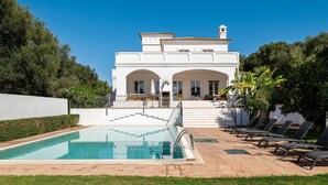 Un edificio blanco grande con piscina y mesas al aire libre.
