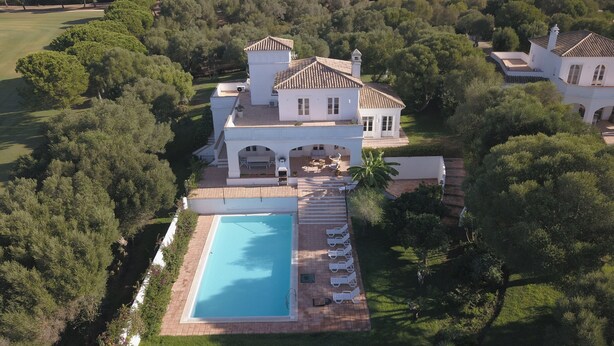 Vista aérea de una extensa propiedad con piscina, varias edificaciones y exuberante vegetación.
