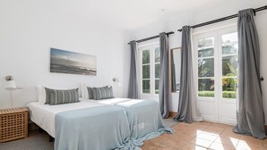 Un dormitorio con cama, cortinas, una ventana, una lámpara y un cuadro.