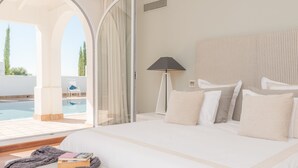 A hotel room with a bed, a lamp, a view of a pool, and a window with curtains.