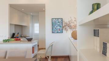 Una cocina moderna con armarios blancos, un comedor con mesa y sillas, y un adorno en la pared.