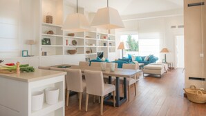 A modern living room with a dining area, white furniture, and a large window.
