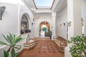 A corridor with a tiled floor, a wooden bench, and potted plants. - Holiday Home 'Iris' with Private Pool, Wi-Fi and Air Conditioning (Benalup-Casas Viejas)