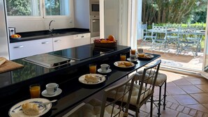 Una cocina moderna con una isla central, espacio para desayunar y vistas al patio exterior.