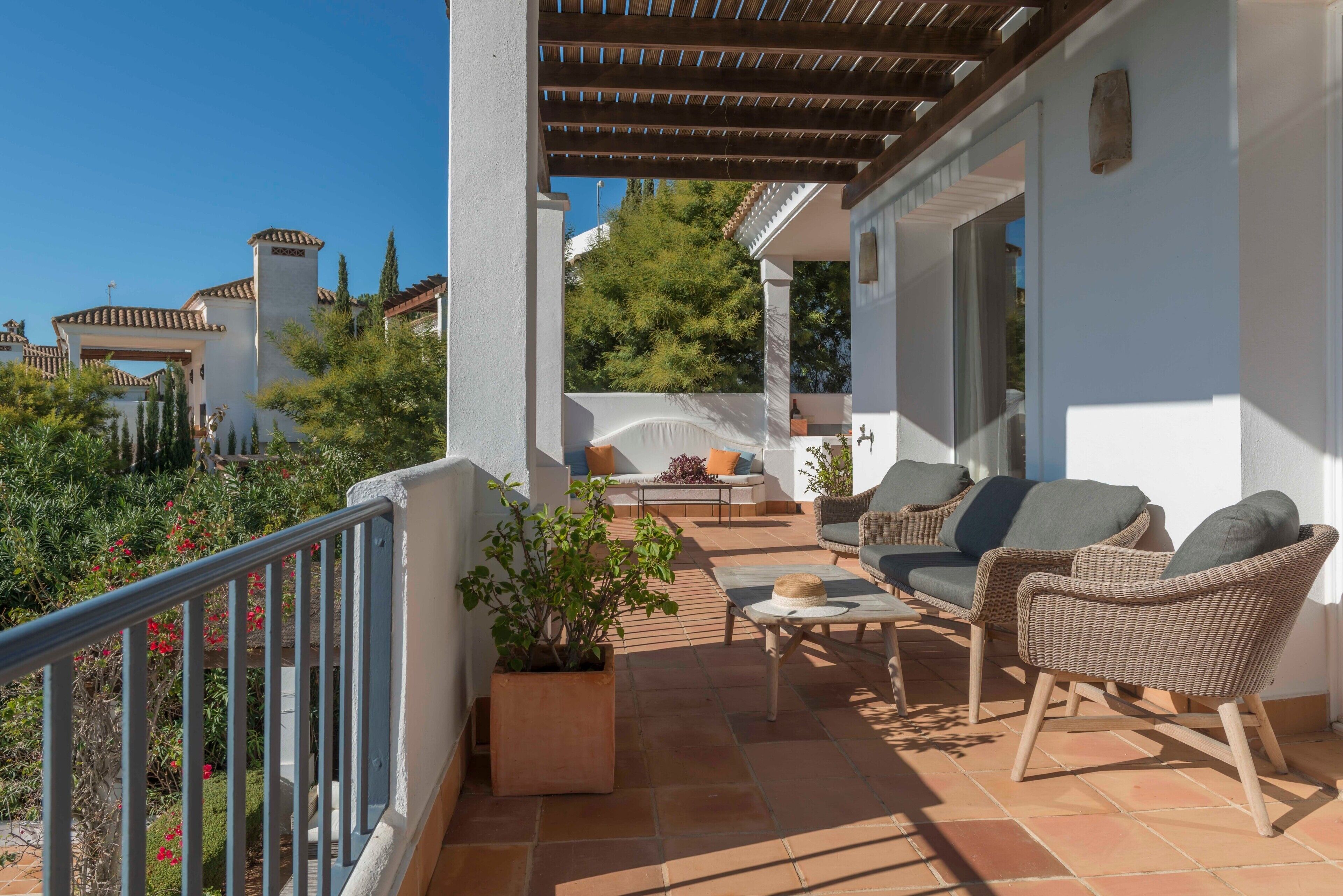 Eine überdachte Terrasse mit Gartenm öbeln, einem Blumentopf und Blick auf die Umgebung.