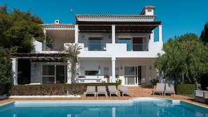 Ein zweistöckiges Haus mit Swimmingpool, Außenbereich und einem gepflegten Garten.
