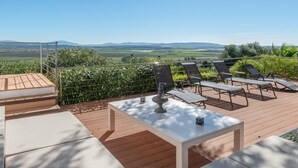 Una terraza con asientos al aire libre, una mesa y vistas al campo.