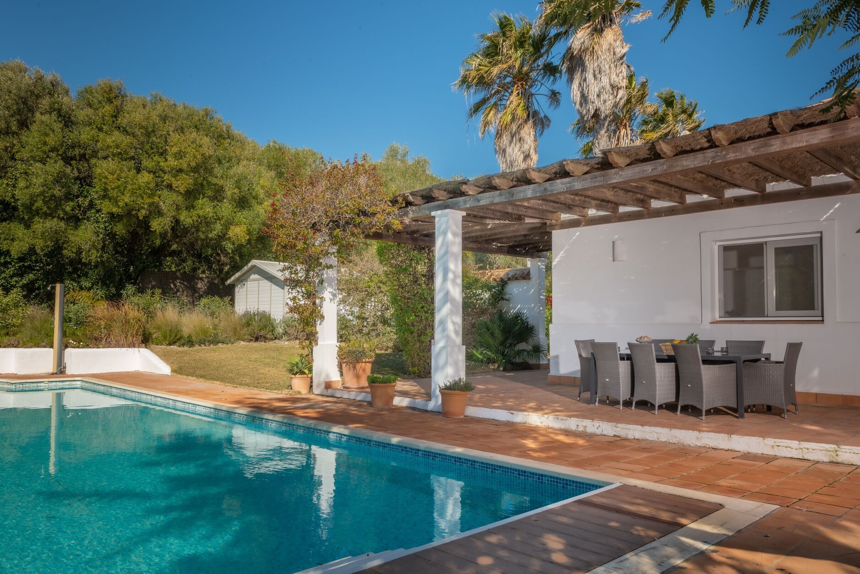 A swimming pool with a pergola and outdoor seating area.