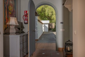 A hallway with a lamp, a fire extinguisher, a door leading outside, and a small birdcage.