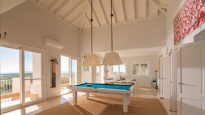 Una habitación amplia con mesa de billar, ventanas grandes y un balcón con vistas.