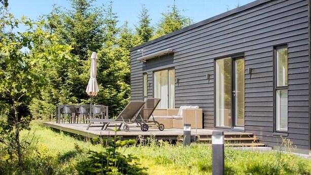 Une maison moderne dotée d’une terrasse, de mobilier d’extérieur et d’une pergola.