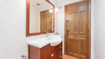A bathroom with a wooden vanity, a white sink, and a large mirror.