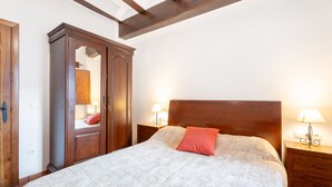 A bedroom with a large bed, wooden wardrobe, and bedside lamps.