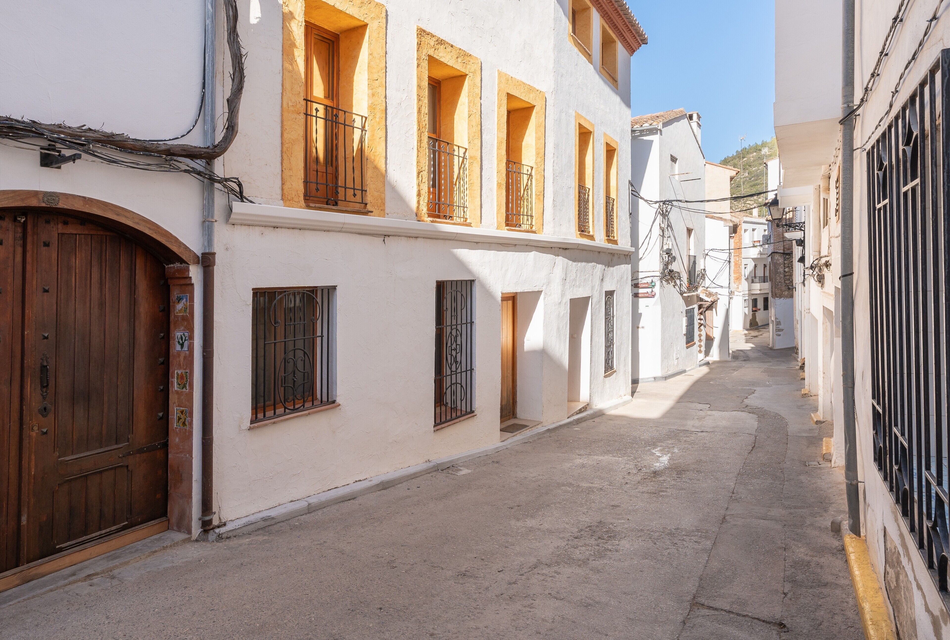 Una calle estrecha con edificios que tienen balcones y una puerta de madera.