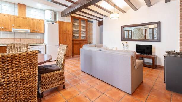 A kitchen with wooden cabinets, a built-in oven, and a dining area with wicker chairs.