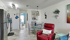 Un salon moderne avec un fauteuil en cuir rouge, un canapé bleu et un coin repas doté d’une table en verre.