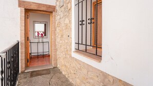 Un pasillo estrecho con pared de piedra, una puerta de madera y una ventana con barrotes.