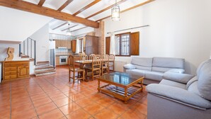 A spacious living area with a dining table, sofa, and kitchen in the background. - Country House 'Cueva De La Portería' with Mountain View and Wi-Fi (Chulilla)