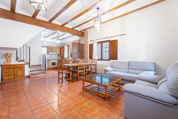 A spacious living area with a dining table, sofa, and kitchen in the background.