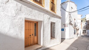 A narrow street with white buildings, a wooden door, and a window with metal bars. - Country House 'Cueva De La Portería' with Mountain View and Wi-Fi (Chulilla)
