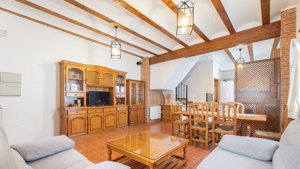 A spacious living area with a wooden coffee table, sofas, a TV, and a fireplace. - Country House 'Cueva De La Portería' with Mountain View and Wi-Fi (Chulilla)