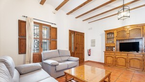 A living room with a sofa, a coffee table, wooden cabinets, and a television. - Country House 'Cueva De La Portería' with Mountain View and Wi-Fi (Chulilla)