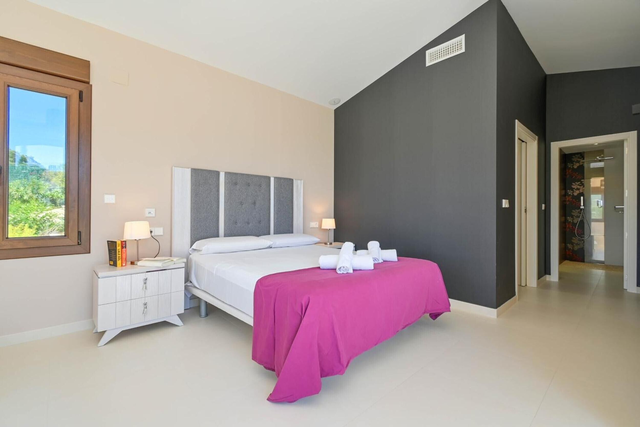 A bedroom with a bed, nightstands, a window, and a door leading to another room.
