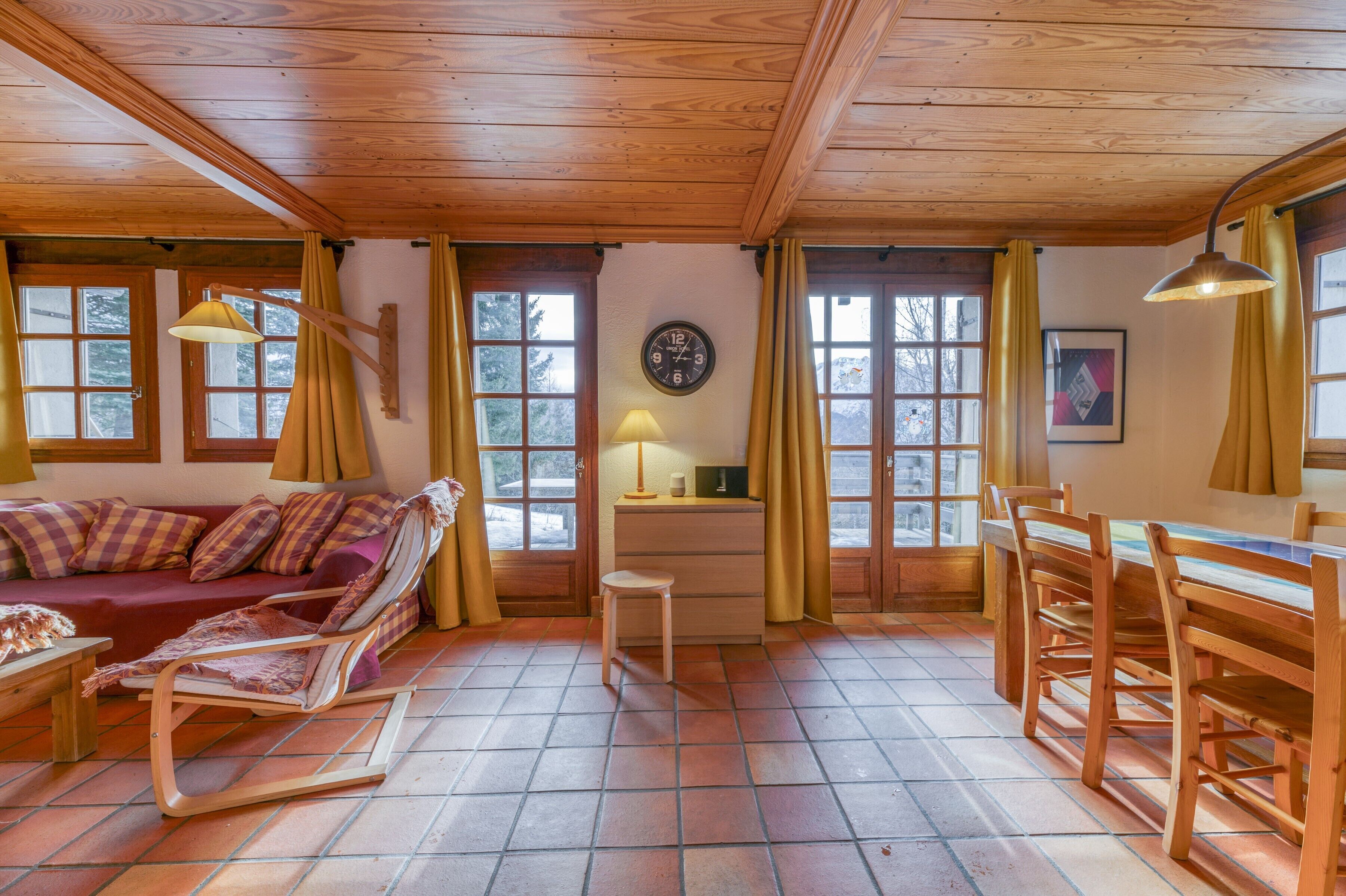 A wooden interior with a sofa, rocking chair, dining table, and chairs.