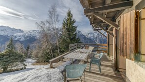 A wooden deck with a table and chairs, overlooking a snowy mountain landscape. - Apartment 'La Salamandre' with Mountain View, Private Terrace and Wi-Fi (Villard-Reculas)