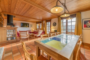 Un intérieur en bois avec un sol carrelé, une table à manger avec des chaises, une bibliothèque et un canapé.