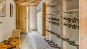 A hallway with wooden flooring, a bench, a wine rack, and a door leading to another room. - Apartment 'La Salamandre' with Mountain View, Private Terrace and Wi-Fi (Villard-Reculas)