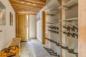 Un couloir doté d’un plancher en bois, d’un banc, d’un meuble à bouteilles et d’une porte donnant sur une autre pièce.