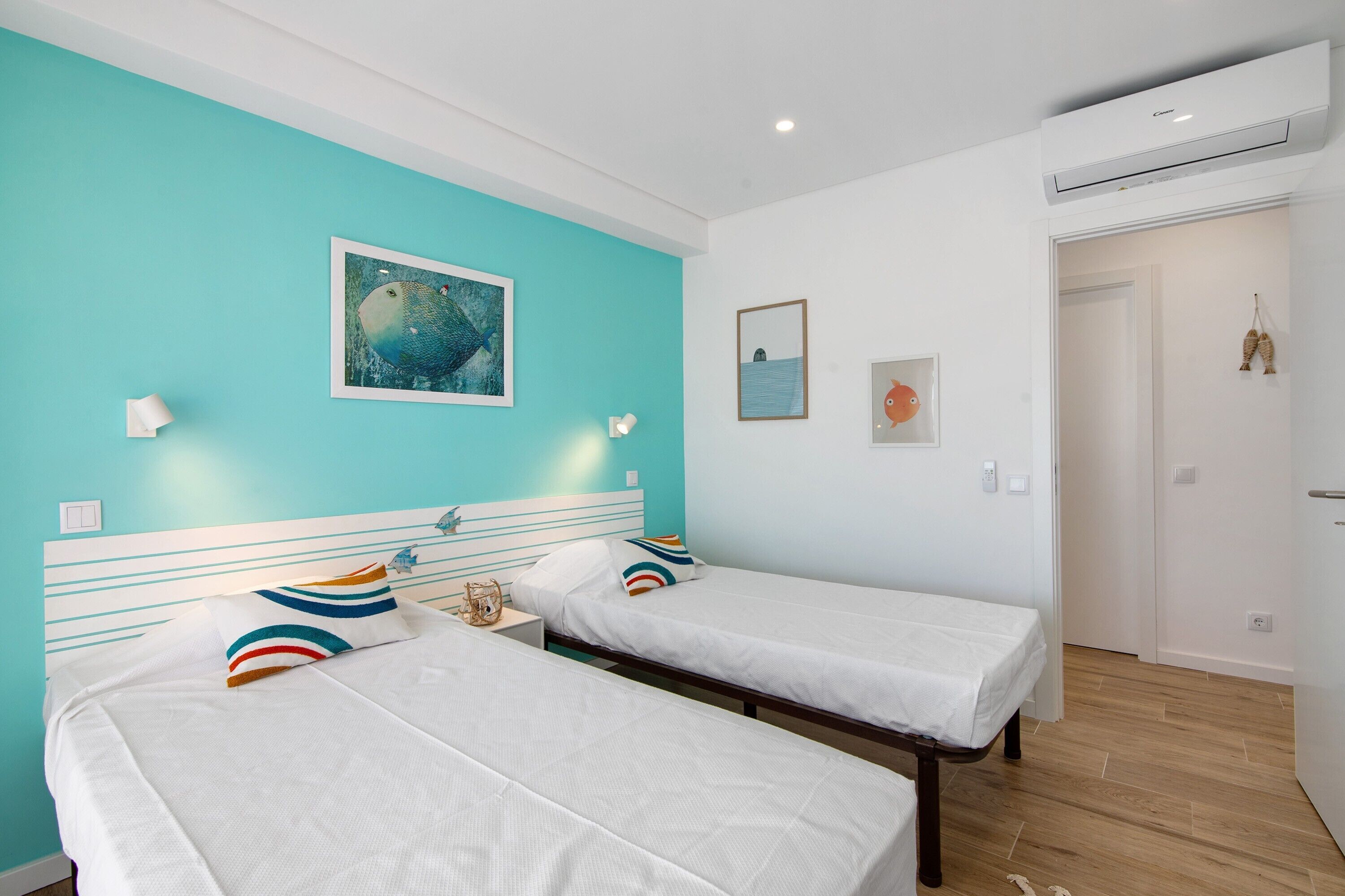Een kamer met twee bedden, een blauwgroene muur en een schilderij.