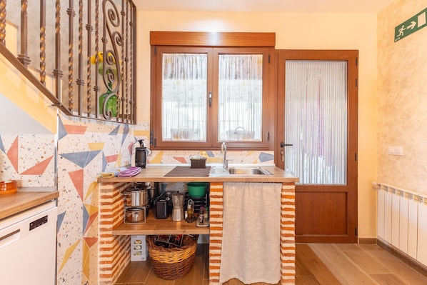 A compact kitchen with a wooden counter, a sink, and a window with curtains.